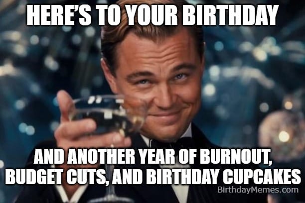 Leonardo DiCaprio giving a sarcastic toast with a paper cup in an office birthday setting.