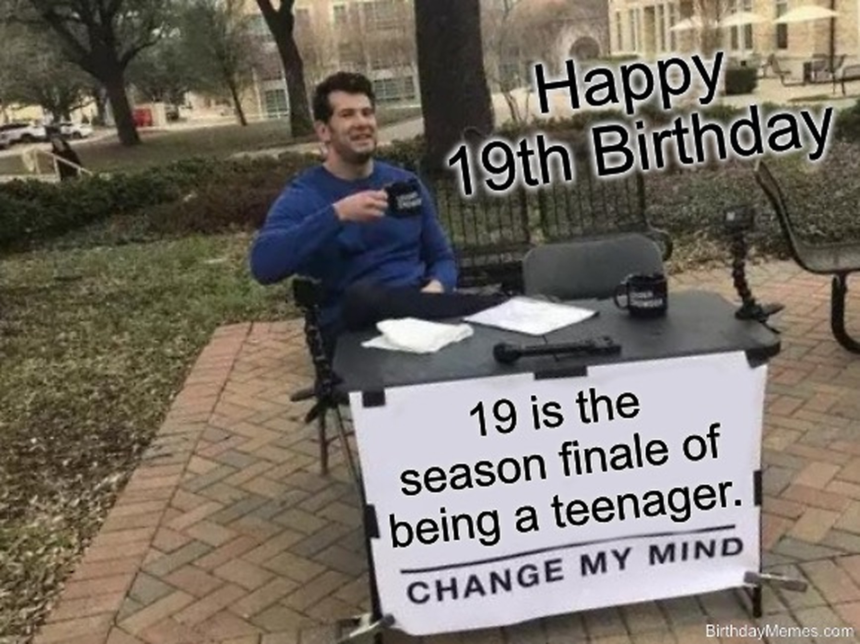 A man sits at a table with a sign that reads '19 is the season finale of being a teenager. Change my mind.' The text says 'Happy 19th Birthday.'